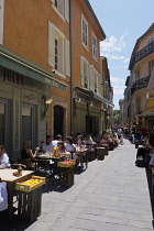 France, Provence-Alpes-Cote d'Azur, Antibes, Narrow street in the Old town with eople sat outside restaurants.