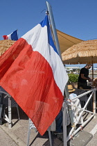 France, Provence-Alpes-Cote d'Azur, Antibes, Tricolour flag flying poutside beach front cafe.