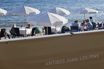 France, Provence-Alpes-Cote d'Azur, Antibes, Juan-les-Pins, Beach front restaurant and bars with parasols on the sandy beach.