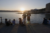 France, Provence-Alpes-Cote d'Azur, Antibes, Juan-les-Pins, People sat on chairs enjoying the sunset from the jetty.