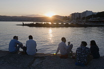 France, Provence-Alpes-Cote d'Azur, Antibes, Juan-les-Pins, People sat on chairs enjoying the sunset from the jetty.