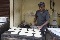 India, Tamil Nadu, Chennai, Man cooking chapati in market.