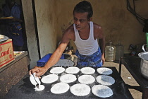 India, Tamil Nadu, Chennai, Man cooking dosa in the market.