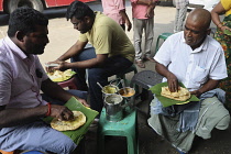 India, Tamil Nadu, Tirupathi, Men eating puri in the market.