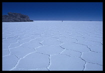 Bolivia, Uyuni, Salt desert, with cracks & person in distance.