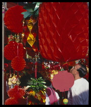 Singapore, Chinatown, Shoppers after work at stall with paper decoration for Chinese New Year.