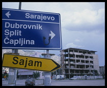 Bosnia, Mostar, Road sign and war damaged building behind.