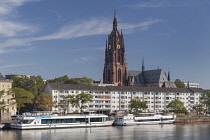 Germany, Hesse, Frankfurt, view of the Main river and the tower of the Kaiserdom Saint Bartholomaus or Frankfurt Cathedral with tourist sightseeing boats moored on the waterfront.