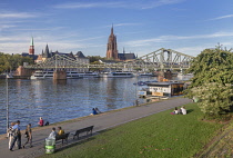 Germany, Hesse, Frankfurt, view of the Main river and the tower of the Kaiserdom Saint Bartholomaus or Frankfurt Cathedral with the Eiserner Steg pedestrian bridge.