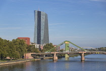 Germany, Hesse, Frankfurt, distant view of the new European Central Bank building from the Eiserner Steg pedestrian bridge with the River Main and the green Alte Brucke bridge.